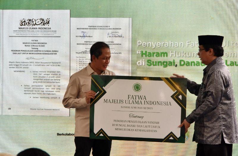 Wasekjen MUI Bidang Ekonomi dan Lingkungan Hidup Hazuarli Halim (kanan) menyerahkan secara simbolis fatwa MUI tentang haram hukumnya membuang sampah di sungai, danau dan laut kepada Menteri Lingkungan Hidup Hanif Faisol Nurofiq (kiri) saat peluncuran di Komunitas Iklim Sungai Cikeas (KISUCI), Babakan Madang, Bogor, Jawa Barat, Minggu (15/2/2026).(Foto: Tera Nusantara.com)